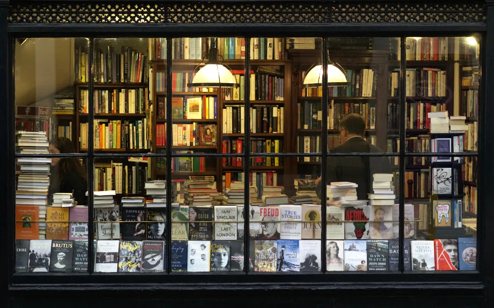 Independent bookshop storefront with a lit window display on a city street
