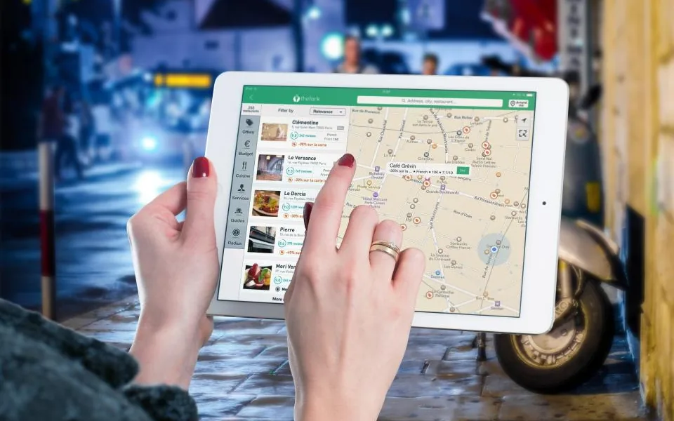 Person browsing a local map search with nearby business listings on a tablet
