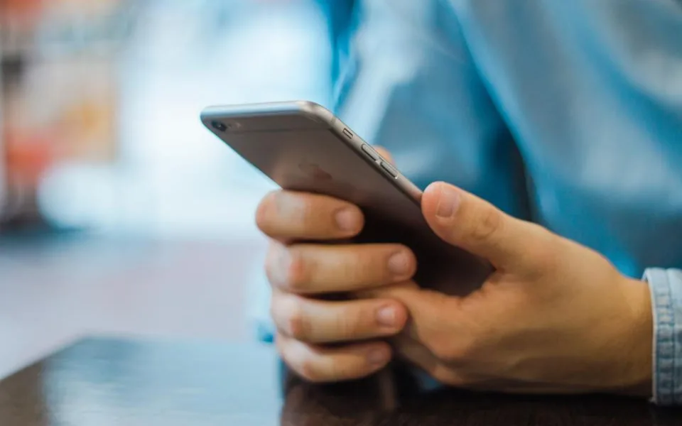 Hands typing a review request text message on a phone