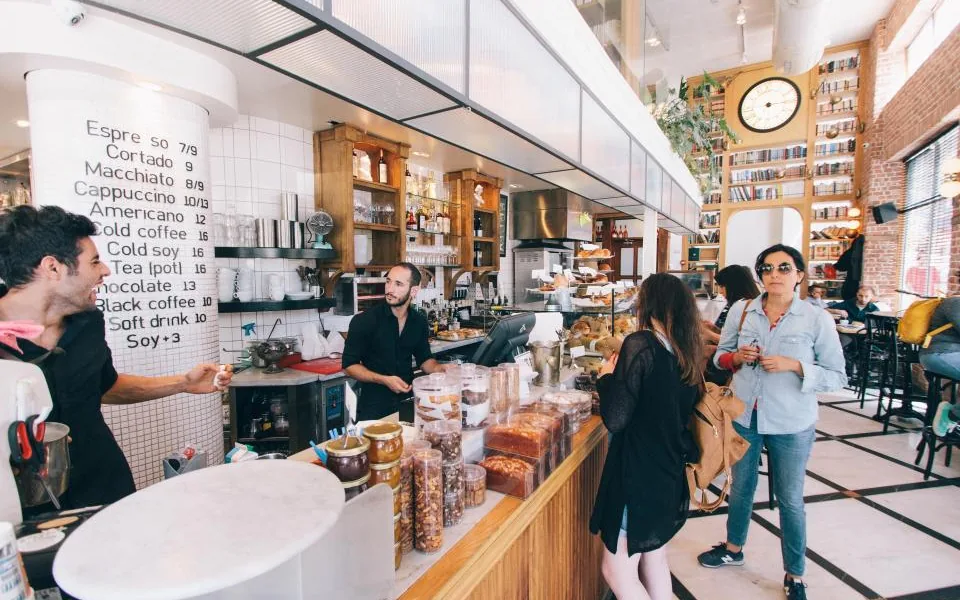 Staff serving customers at the counter of a busy local cafe