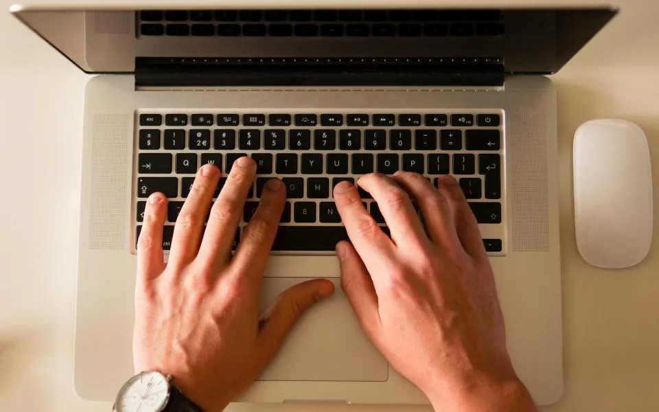 Hands typing review replies on a laptop keyboard at an office desk