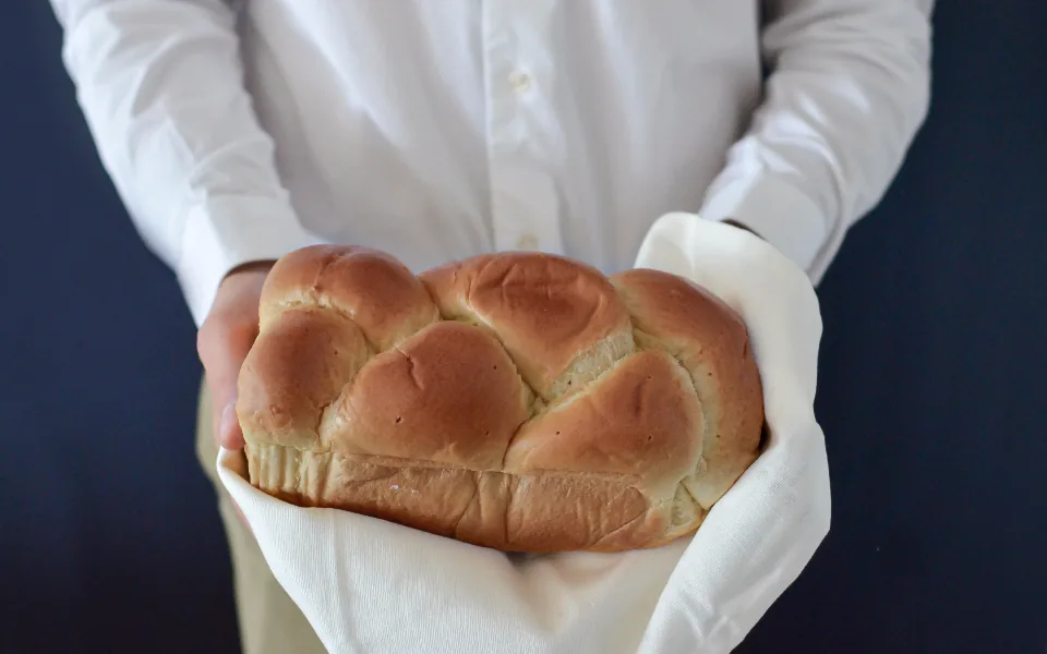 Local bakery owner holding a freshly baked loaf of bread